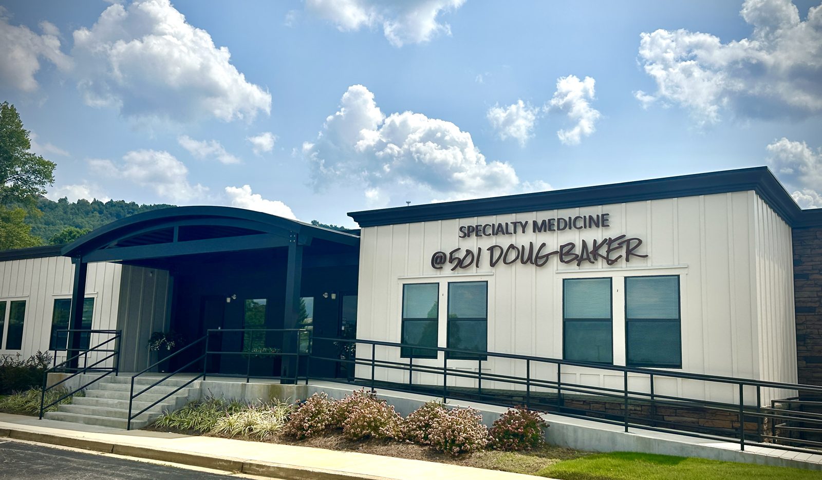The Hoover office at 501 Doug Baker Boulevard: a white board-and-batten building with a dark curved entry canopy, a ramp and steps to the front doors.